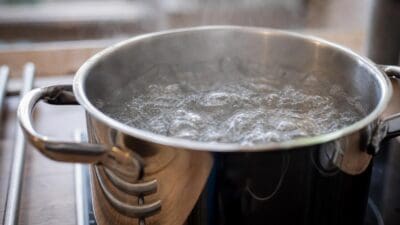 Großer Edelstahltopf mit sprudelnd kochendem Wasser auf einem Herd