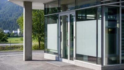 Eingang mit großen Glasflügeltüren an einem modernen Gebäude vor Berglandschaft