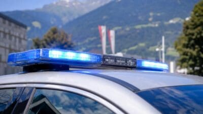 Blaues Blaulicht auf dem Dach eines silbernen Polizeifahrzeugs vor Bergpanorama