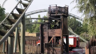 Verkohlter Holzturm unter den Schienen der Achterbahn Raptor mit Feuerwehrfahrzeugen