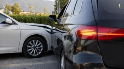 Ein weißes und ein schwarzes Auto nach einer Kollision auf einem Parkplatz mit Bergen im Hintergrund