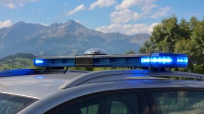 Blaues Blaulicht leuchtet auf dem Dach eines Polizeifahrzeugs vor einer Berglandschaft