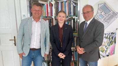 Christian Scheider, Clara-Milena Steiner und Hannes Mößlacher stehen vor einem Bücherregal im Büro.