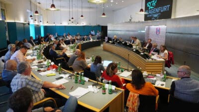 Blick in den Sitzungssaal des Klagenfurter Gemeinderats mit zahlreichen Ratsmitgliedern an langen Tischen