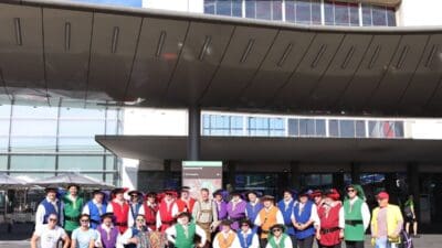 Gruppe von Personen in bunten Trachten und mit Akkordeon vor dem Grazer Hauptbahnhof