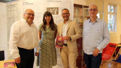 Vier Personen stehen vor einem Banner und präsentieren das Buch Unerwidert lieben im Musilmuseum.