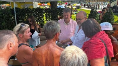 Gruppe von Menschen im Gespräch unter einem weißen Zelt im Strandbad Klagenfurt