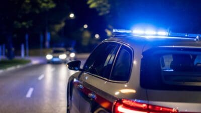 Polizeifahrzeug mit blauem Blaulicht und roten Rücklichtern auf nächtlicher Straße
