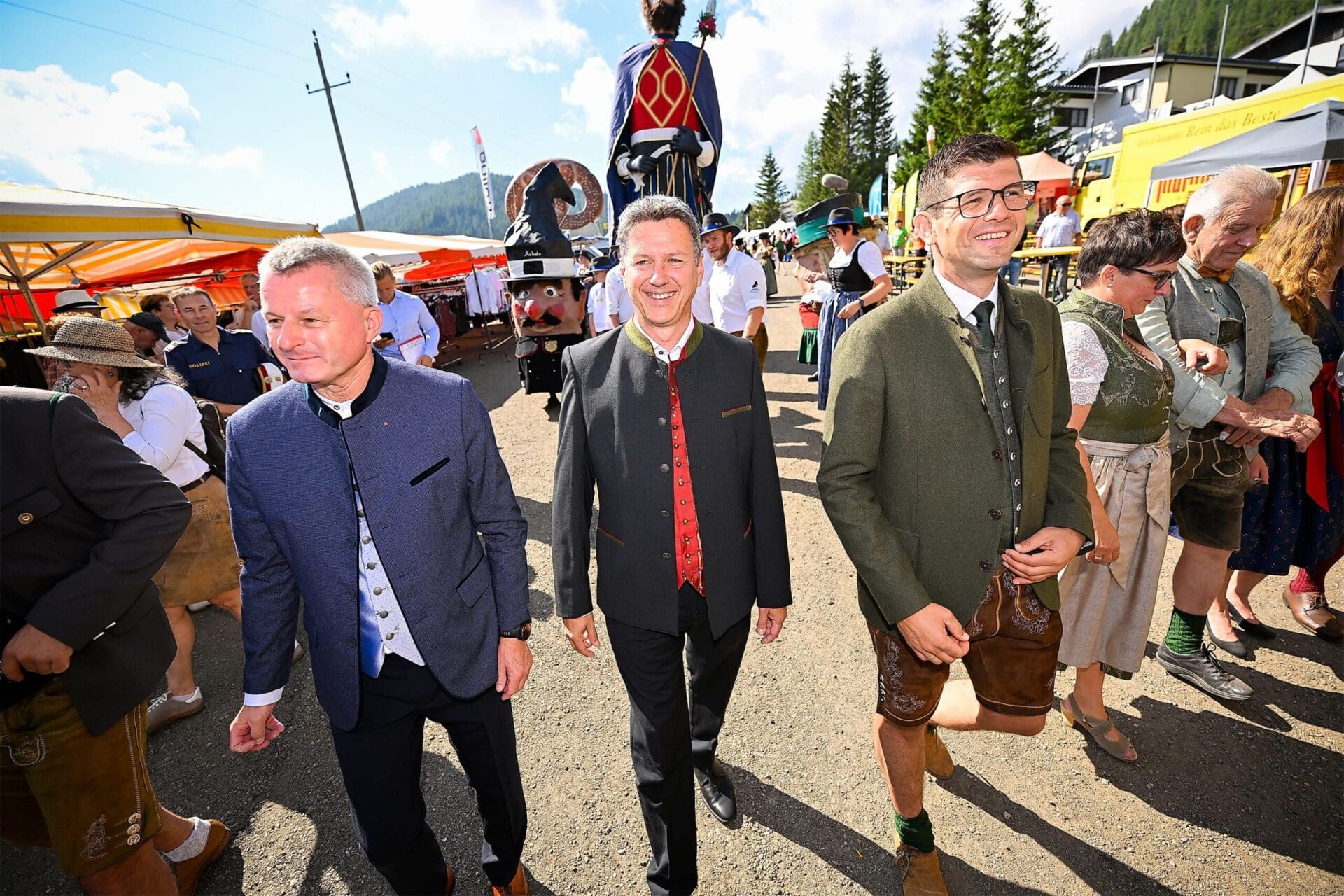 Zwei Männer in traditioneller Tracht gehen lächelnd über ein Festgelände auf der Flattnitz.