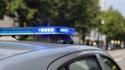 Nahaufnahme eines aktivierten blauen Blaulichts auf dem Dach eines grauen Polizeifahrzeugs