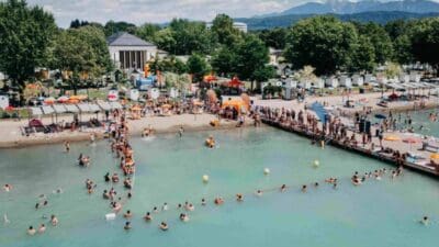 Viele Menschen im türkisfarbenen Wasser und auf dem Steg beim Familienfest im Strandbad Klagenfurt