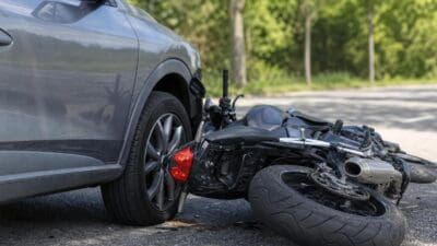 Graues Auto und umgestürztes schwarzes Motorrad nach Unfall auf der Straße