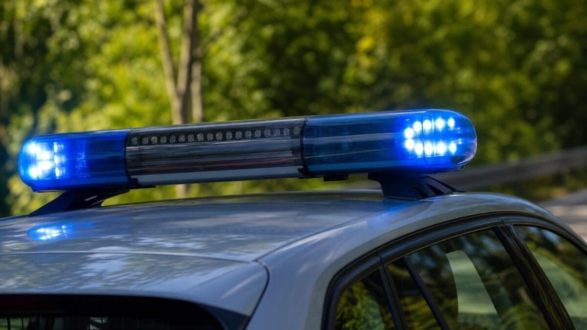 Blaues Blaulicht leuchtet auf dem Dach eines silbernen Polizeifahrzeugs.