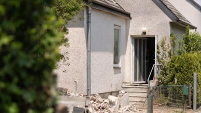 Beschädigtes Einfamilienhaus mit Trümmern und offenem Eingang in Floridsdorf