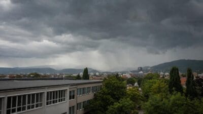 Dunkle Gewitterwolken mit Regenschauer über Graz und umliegenden Gebäuden