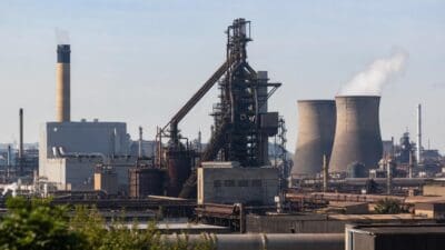 Industrieanlage mit Hochofen, Kühltürmen und Schornstein unter blauem Himmel
