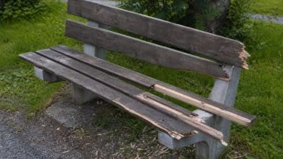 Beschädigte Holzbank mit herausgerissenen Latten auf einer Wiese