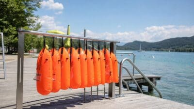 Orange Schwimmbojen hängen an einem Metallgeländer am Steg eines Strandbads