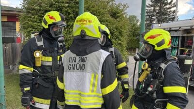 Mehrere Feuerwehrleute der Feuerwehr Gmünd in Schutzkleidung und Atemschutz stehen zusammen.