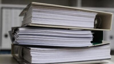 Mehrere Stapel von Aktenordnern mit dicken Papierbündeln auf einem Tisch