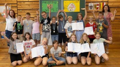 Gruppe von Schülerinnen und Schülern mit Urkunden und Medaillen vor einer Schultafel in Guttaring