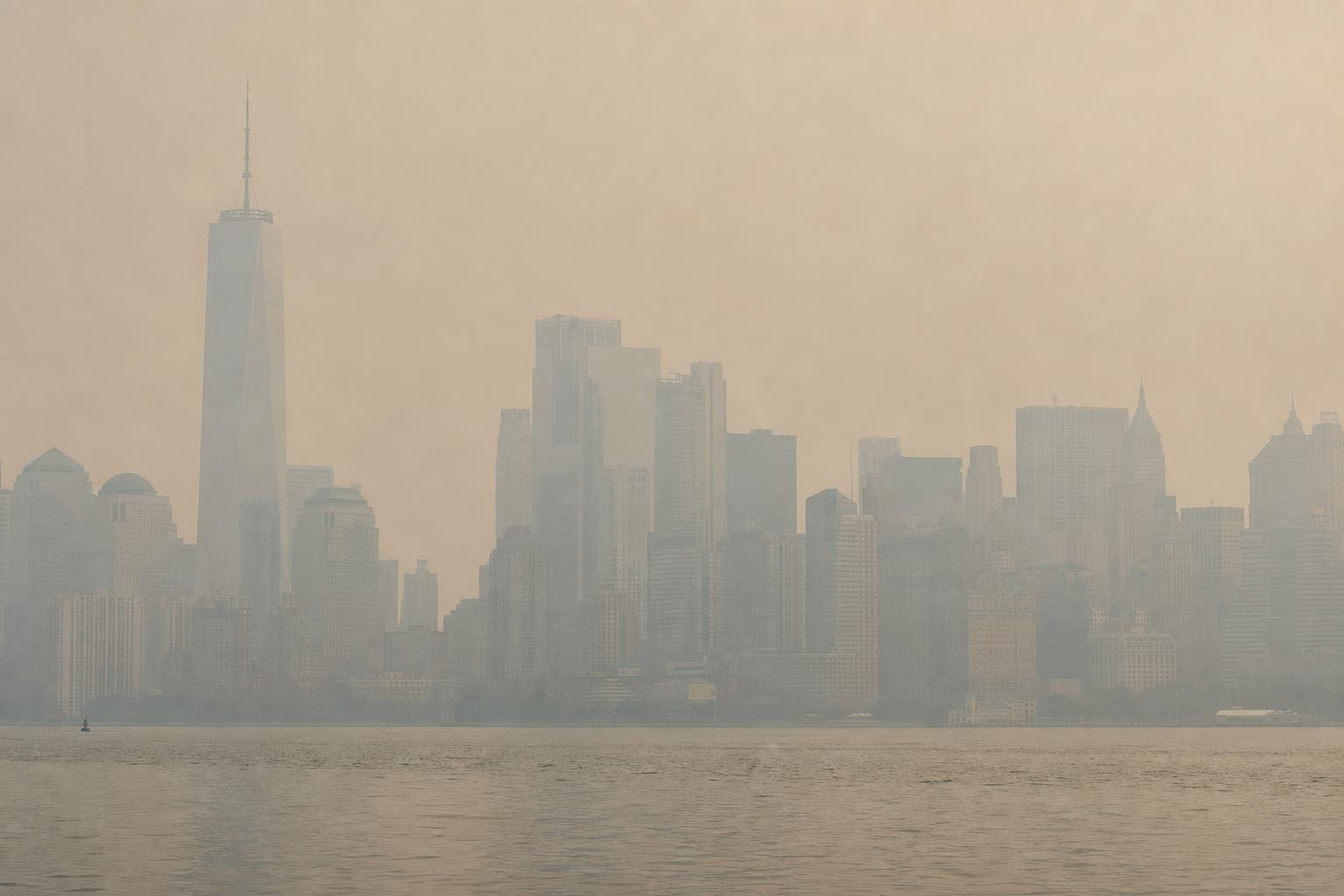 New Yorker Skyline mit One World Trade Center hinter dichter Rauchschicht über dem Wasser