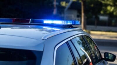 Nahaufnahme eines silbernen Polizeifahrzeugs mit aktiviertem blauem und rotem Blaulichtbalken