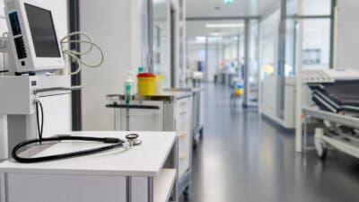 Stethoskop liegt auf einem Tisch neben einem medizinischen Monitor in einem Krankenhausflur