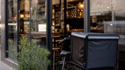 Lastenrad mit schwarzer Lieferbox vor Glasfront eines Restaurants