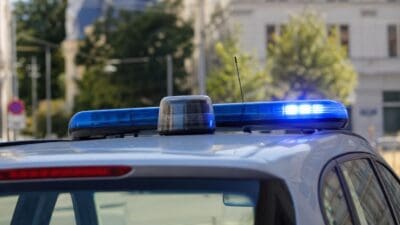 Nahaufnahme eines aktivierten blauen Blaulichts auf einem Polizeifahrzeug in städtischer Umgebung.