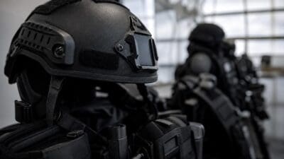 Nahaufnahme eines schwarzen taktischen Helms und einer Schutzweste mit Ausrüstung.