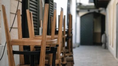 Gestapelte Holzstühle mit schwarzen Gestellen in einem schmalen Durchgang