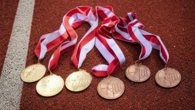 Goldene und bronzene Medaillen mit rot-weißen Bändern auf einer roten Laufbahn