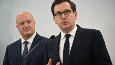 Markus Gstöttner spricht gestikulierend in ein Mikrofon, hinter ihm steht ein älterer Mann.