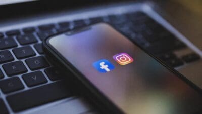 Smartphone mit den Symbolen der Apps Facebook und Instagram auf einer Laptop-Tastatur