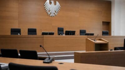 Leerer Gerichtssaal mit Holzvertäfelung, Richterbank und großem silbernem Bundesadler an der Wand