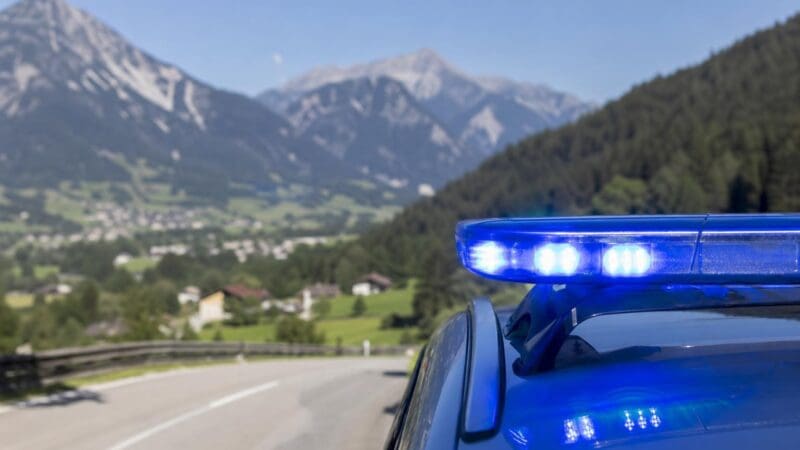 Blaues Blaulicht auf dem Dach eines Einsatzfahrzeugs vor einer Berglandschaft