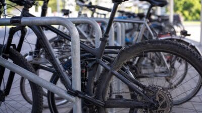 Schwarzes Mountainbike an einem Metallfahrradständer mit weiteren Rädern im Hintergrund am Bahnhof Völs