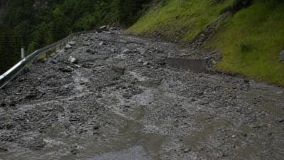 Schlamm und Geröll bedecken eine Bergstraße mit Leitplanke im Ötztal