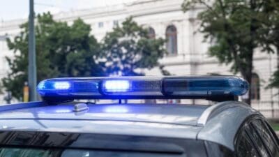 Leuchtendes blaues Blaulicht auf dem Dach eines Polizeifahrzeugs vor einem Gebäude