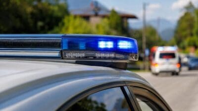 Blaues Blaulicht auf dem Dach eines Polizeifahrzeugs mit Rettungswagen im Hintergrund