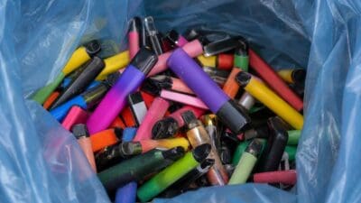 Offene blaue Plastiktüte mit vielen bunten Einweg-E-Zigaretten in verschiedenen Farben.