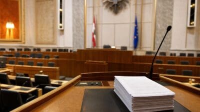 Leerer Plenarsaal des Nationalrats mit Stapel von Dokumenten auf dem Rednerpult