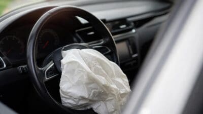 Ausgelöster weißer Airbag im Lenkrad eines Autos