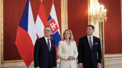 Drei Politiker stehen vor den Flaggen Tschechiens, Österreichs und der Slowakei in einem prunkvollen Saal