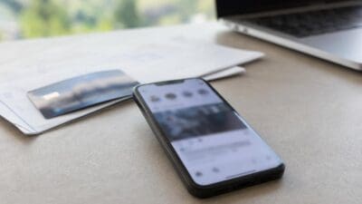 Smartphone mit geöffneter App auf dem Display neben Kreditkarte und Papieren auf einem Tisch