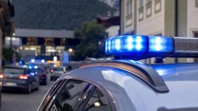 Blaues Blaulicht auf dem Dach eines Polizeifahrzeugs in einer Straße mit Bergen im Hintergrund
