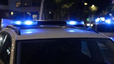 Dach eines weißen Polizeifahrzeugs mit leuchtendem Blaulicht in der Nacht