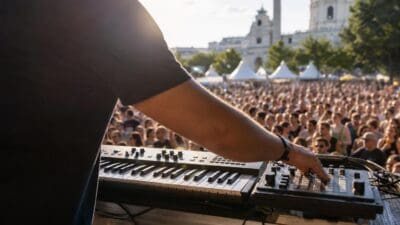 Ein Musiker bedient ein Keyboard vor einer großen Menschenmenge mit der Karlskirche im Hintergrund.