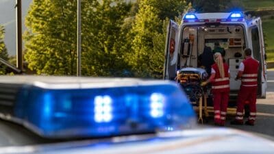 Sanitäter laden einen Patienten auf einer Trage in einen geöffneten Rettungswagen